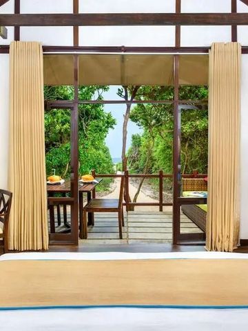 Geräumiges Zimmer mit Blick auf eine tropische Terrasse und grüne Umgebung