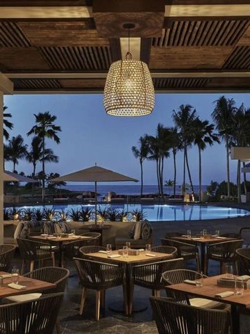 Restaurantbereich im Freien mit Blick auf beleuchteten Pool und Palmen