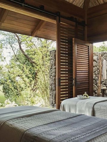 Spa-Behandlungsbereich im Freien mit zwei Massagetischen und grüner Umgebung.