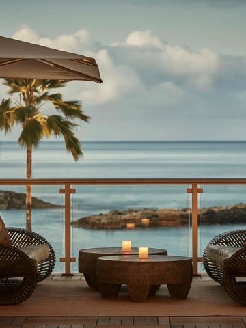 Terrasse mit Meerblick, entspannte Sitzgelegenheiten, Palmen am Horizont