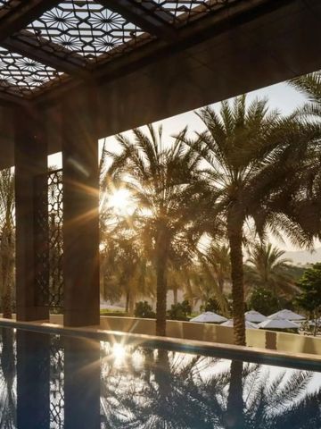 Pool mit Palmen im Hintergrund bei Sonnenuntergang