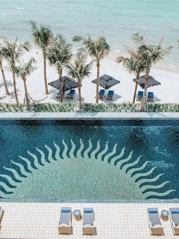 Infinity-Pool am Meer mit Palmen und blauer Liegefläche