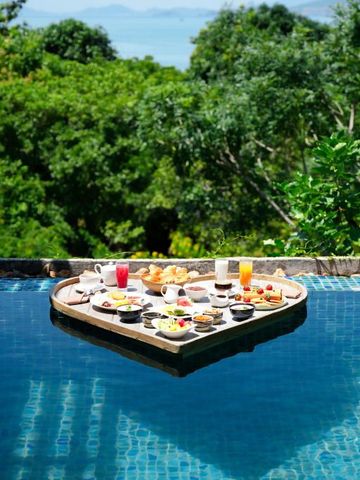 Pool mit schwimmendem Frühstückstablett vor üppiger grüner Landschaft