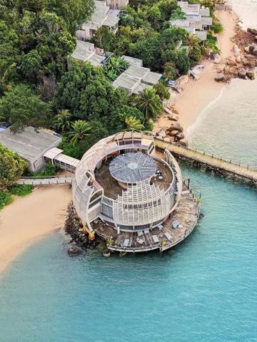 Luftaufnahme eines runden Gebäudes am Strand umgeben von tropischer Vegetation