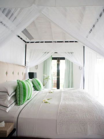 Helles Schlafzimmer mit Himmelbett und grünen Akzenten