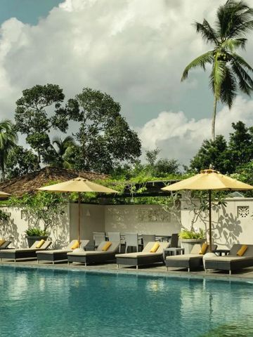 Sonnenschirme und Liegen am Außenpool mit üppiger Vegetation