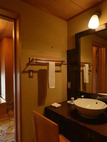 Elegantes Badezimmer mit Waschbecken und Holzverkleidung im Iki Retreat