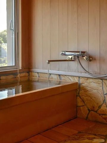Japanisches Badezimmer mit hölzernem Onsen-Bad und Fenster mit Ausblick