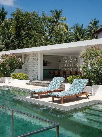 Luxuriöser Poolbereich mit Sonnenliegen und tropischem Garten