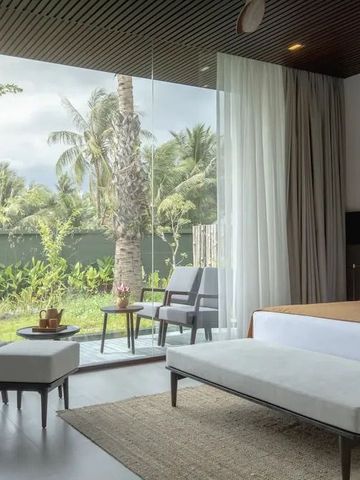 Modernes Hotelzimmer mit großem Fenster und Blick auf tropischen Garten