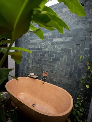 Freiluft-Badezimmer mit Natursteinmauer und stilvoller Badewanne