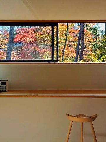 Autumnale Waldlandschaft durch ein modernes Fenster in einem minimalistischen Raum
