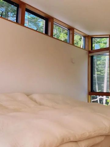 Minimalistisches Schlafzimmer mit großen Fenstern und direktem Blick auf die Natur