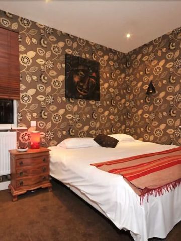 Schlafzimmer mit Doppelbett und dekorativer Tapete in Braun- und Beigetönen