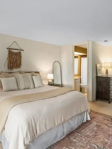 Hotelzimmer mit gemütlichem Bett und modernen Möbeln, warm beleuchtet.