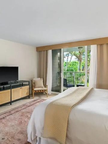 Hotelzimmer mit TV und Balkon, Blick auf grüne Umgebung durch Fenster.