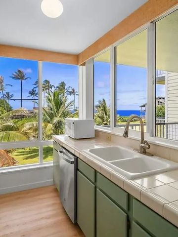 Heller Raum mit Küchenzeile und Blick auf Palmen und Meer