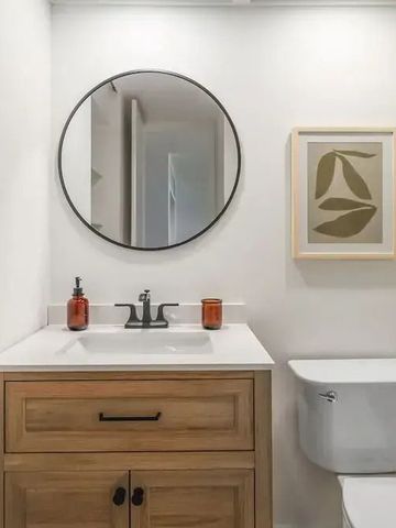 Elegantes Badezimmer mit rundem Spiegel und moderner Ausstattung