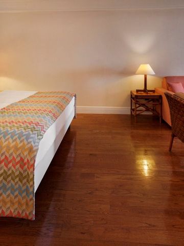 Hotelzimmer mit gemütlicher Sofaecke und Doppelbett auf Holzboden