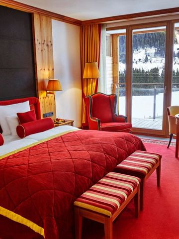 Luxuriöses Hotelzimmer mit rotem Interieur und Blick auf verschneites Panorama