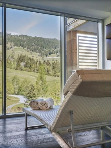 Zimmer mit Blick auf grüne Berglandschaft durch große Fenster und bequeme Liege.