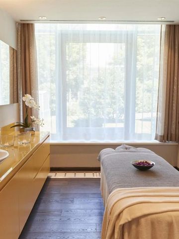 Heller Behandlungsraum im Spa mit Massagetisch und großem Fenster zur Natur.