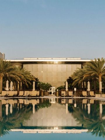 Großer Außenpool mit Liegestühlen und Palmen im Sonnenuntergang