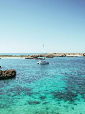 Türkisblaues Meer mit Segelboot und felsiger Küstenlandschaft