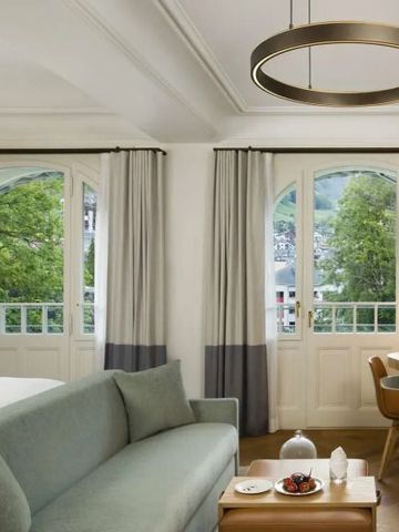 Geräumiges Hotelzimmer mit Sofa und Balkonblick auf die Natur