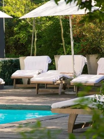 Sonnenschirme und Liegen am Pool mit grüner Umgebung