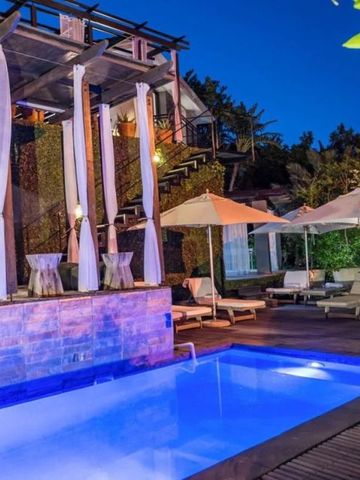 Außenansicht des Pools bei Nacht mit Liegestühlen und Sonnenschirmen.