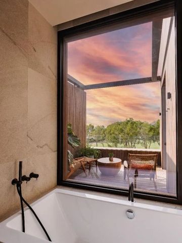 Badewanne mit Aussicht auf Terrasse und buntem Abendhimmel.