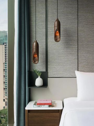 Hotelzimmer mit seitlichem Blick auf die Stadt und stilvollen Hängeleuchten.