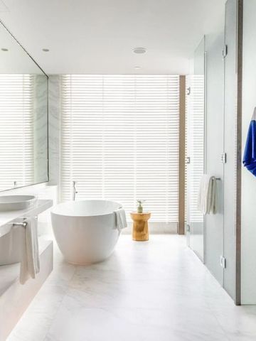 Helles Badezimmer mit freistehender Badewanne und Bademantel an der Tür