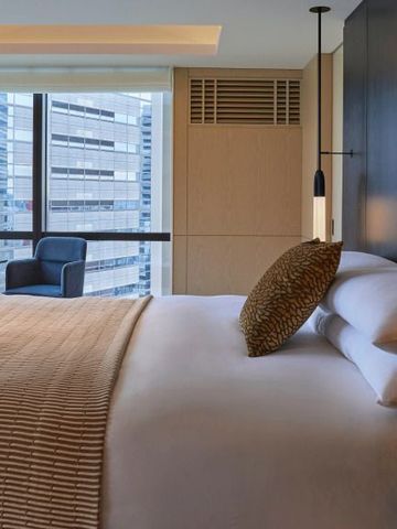 Helles Hotelzimmer mit Doppelbett und Aussicht auf die Stadt.