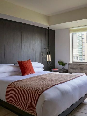 Modernes Hotelzimmer mit großem Bett, hellem Fenster und stilvollem Design