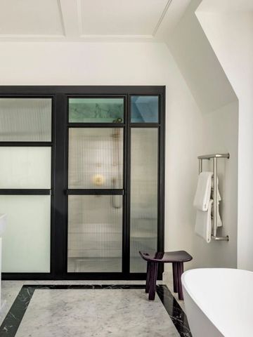 Modernes Badezimmer mit freistehender Badewanne und Glastüren.