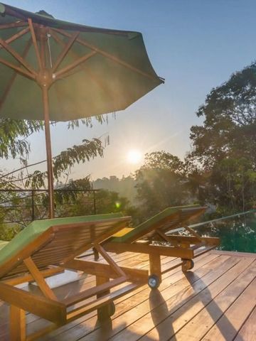 Sonnenliegen auf Holzterrasse mit Blick auf den Pool und Sonnenuntergang