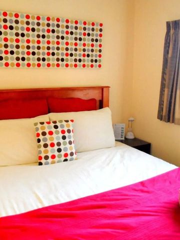 Helles Zimmer mit rot-weißem Akzent und Doppelbett