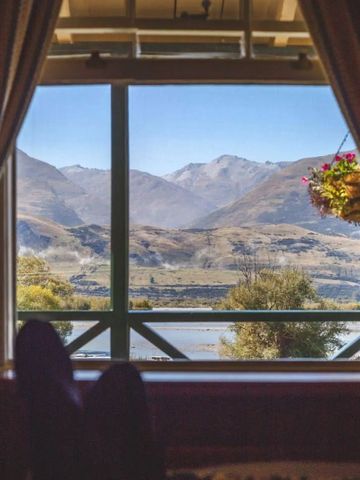 Aussicht vom Zimmer auf Berge und See durch ein Fenster mit Vorhängen
