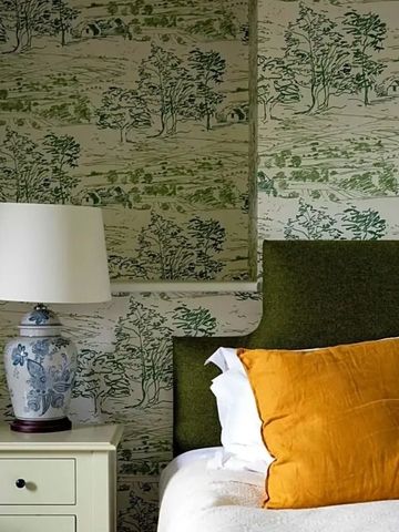 Schlafzimmer mit floralem Tapetenmuster und farbigem Kissen