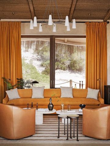 Gemütliche Lounge mit gelben Sofas und großen Fenstern mit Blick auf die Dünen