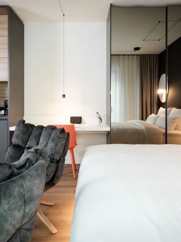 Gemütliches Hotelzimmer mit Doppelbett und eleganter Sitzgelegenheit in warmen Tönen