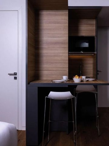 Moderne Kochnische mit Barhockern in stilvollem Hotelzimmer