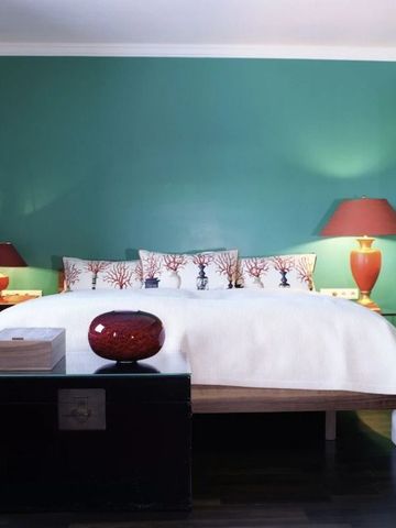 Doppelbett mit kunstvollen Kissen und grüner Wand