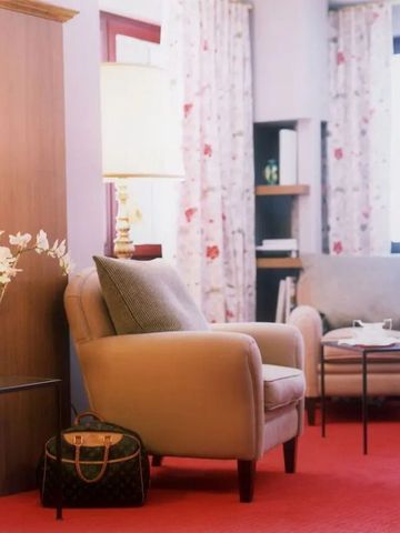 Gemütlicher Sitzbereich in einem Hotelzimmer mit rotem Teppich und eleganten Sesseln