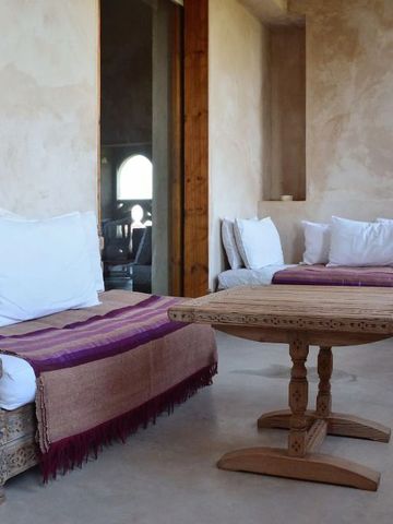 Behagliche Sitzecke mit dekorativen Polstern und rustikalem Tisch im Ksar Char-Bagh
