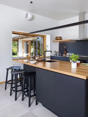 Moderne Küche mit dunkler Arbeitsplatte und Sitzgelegenheiten an der Theke