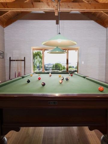 Einladender Billardraum mit großen Fenstern und Holzdecke