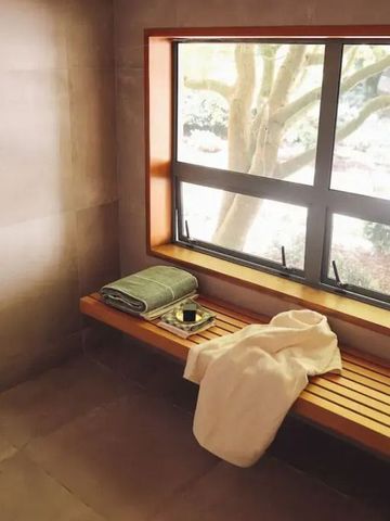 Saunaruheraum mit Holzbank und Handtüchern vor einem großen Fenster